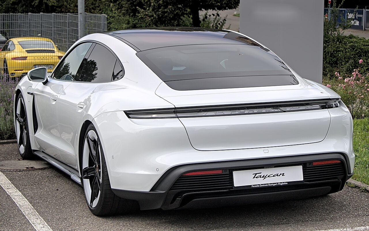 Weißer Porsche Taycan von hinten auf einem Parkplatz