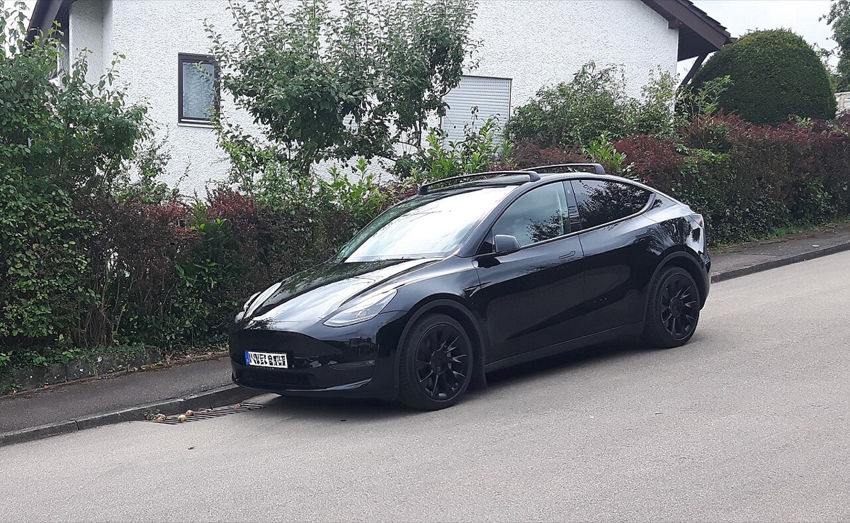 Schwarzes Tesla Model Y am Straßenrand in einem Wohngebiet